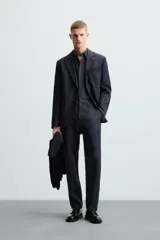 Pantalón de vestir azul marino, de corte recto, confeccionado en lino. Tiene bolsillos laterales y traseros con botón.