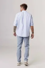 Camisa celeste a rayas verticales blancas, de corte clásico, manga larga y cuello abotonado.