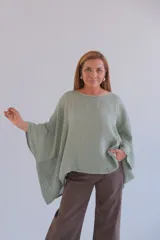 Blusa verde claro de lino, de corte holgado y mangas anchas con detalle de tejido calado en los laterales.