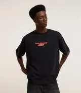 Remera negra de algodón con estampa de duraznos y texto "Bieber's Peaches" en color naranja.