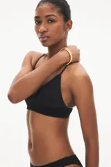 Top de bikini negro con copas de triángulo con relleno extraíble, breteles finos ajustables y tiras cruzadas en la espalda.