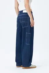 Pantalón jean negro de corte amplio y estilo carpenter, con tiro medio, bolsillos utilitarios y presillas laterales.