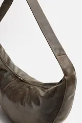 Bolso de hombro color marrón oscuro fabricado en piel con acabado craquelado. Tiene un compartimento principal con cierre de cremallera y un bolsillo interior con cremallera.