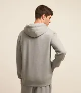 Saco deportivo gris de algodón y poliéster, con capucha ajustable con cordón, cierre frontal con cremallera, mangas largas con puños ajustados y bolsillos laterales.