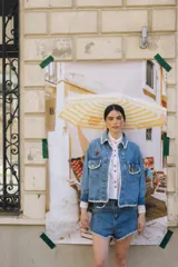 Campera de jean celeste con cuello camisero, cierre frontal con botones metálicos, bolsillos de parche en el pecho con solapa y detalle de puntilla blanca en cuello, solapas, bolsillos y ruedo.