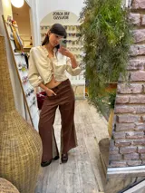 Pantalón sastrero color beige de lino, corte recto y tiro alto, con bordado de caballo en el bolsillo trasero.