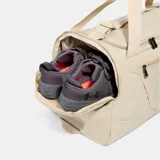 Bolso deportivo Under Armour Undeniable 5.0 mediano, color beige con logo de la marca en el frente. Cuenta con doble asa de mano, correa de hombro ajustable y múltiples bolsillos con cierre.