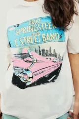 Remera color crema de corte oversized, con estampado de una patente con el nombre de Bruce Springsteen y un auto clásico rosa. Cuello redondo ribeteado.