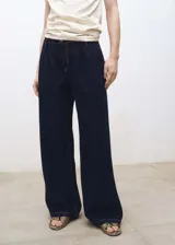 Pantalón de jean azul oscuro, de corte wideleg, tiro medio, con pinzas delanteras, bolsillos laterales y traseros.