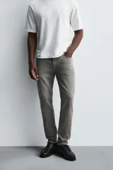 Pantalón de jean negro, corte slim fit, con tiro medio, cinco bolsillos, efecto lavado y cierre frontal con cremallera y botón.