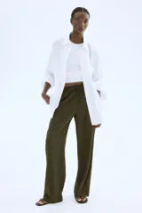 Pantalón verde militar de corte holgado en tejido liviano de mezcla de lino. Modelo de tiro alto con cintura elástica y cordón para ajustar fino, bolsillos laterales discretos y piernas rectas.