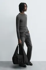 Bolso shopper negro de hombro fabricado en tejido técnico. Tiene un compartimento principal sin cierre, un bolsillo plano y otro con cierre mediante cremallera en el interior. En la parte frontal tiene dos bolsillos con cierre mediante imán y asa de mano.