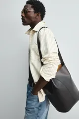 Bolso tipo shopper color marrón, fabricado en piel. Tiene un compartimento principal con cierre de imán y un bolsillo plano interior. El asa de hombro también es de piel.