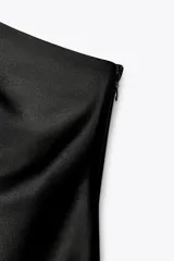 Vestido midi negro de satén, con escote asimétrico y tirante fino.