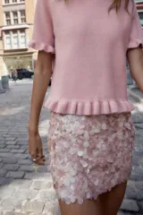 Falda corta de corte recto, completamente cubierta de lentejuelas redondas en tonos plateados y marrones/bronce. Posee forro interior y cierre lateral oculto.