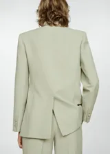 Blazer color verde claro, con cuello de pico con solapa y solapas con muesca. Tiene forro interior, manga larga con puños abotonados, dos bolsillos de solapa en la parte delantera y cierre delantero con botones.