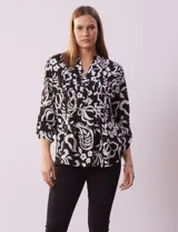 Blusa de gasa estampada en blanco y negro, marca Zac & Rachel. Cuello a la base con escote en V y abertura central con botones. Delantera con detalle plisado. Largo de manga regulable con presilla y botón.