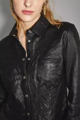 Camisa de cuero ovino color negro, de corte jeanero, con bolsillos tipo ojal en el delantero y cierre frontal con broches a presión con el logo de Rapsodia.