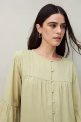 Camisa celeste de corte holgado con botones frontales, canesú con tablas y mangas 3/4 amplias con puño elastizado.