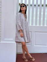 Vestido corto negro de lino, con escote en V, botones frontales y mangas largas acampanadas con volados.