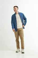 Camisa de denim azul con cuello clásico, cierre frontal con botones a presión, dos bolsillos con solapa abotonada en el pecho y mangas largas con puños abotonados.