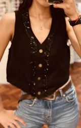 Chaleco negro con botones y detalles de lentejuelas en el escote y en el frente.