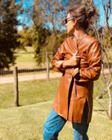 Tapado de cuero color suela, de corte recto, con cuello mao y cierre frontal con botones a presión.