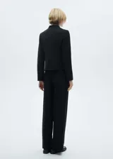 Pantalón negro de corte wide leg, tiro medio, con trabillas, bolsillos laterales y traseros. Cierre frontal oculto con botón, gancho y cremallera.