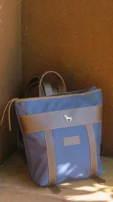Mochila de lona azul con detalles en cuero, incluye mangos regulables para mayor comodidad.