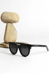 Lentes de sol negros marca Urban Haus, modelo Afrodita, con montura cuadrada gruesa y lentes oscuros.