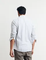Camisa sport de algodón con cuello button-down y manga larga. Diseño a rayas verticales en tonos gris y blanco. Cierre frontal con botones de madera.