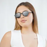 Lentes de sol con montura redonda color gris y detalles dorados en las patillas.