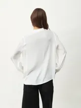 Blusa blanca de manga larga con escote en V y textura arrugada.