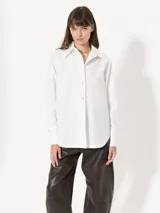 Camisa de poplin blanca con botones metálicos en el delantero y puños, de corte clásico y manga larga.