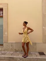 Vestido corto amarillo con lunares marrones, escote drapeado y tirantes finos.