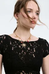 Collar dorado con cadena de eslabones y dijes colgantes con forma de sol, cerezas, conchas marinas y ajíes.