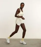 Short deportivo femenino color blanco, de poliéster, con cintura elástica, abertura lateral y bolsillo trasero.