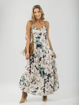 Vestido largo con estampado floral en tonos blanco, beige y verde sobre fondo negro. Diseño con breteles finos y corte amplio.
