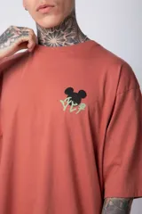 Remera blanca de algodón de corte oversize con mangas cortas y cuello redondo. Presenta un pequeño estampado en el frente con la figura de Mickey Mouse y caracteres orientales.