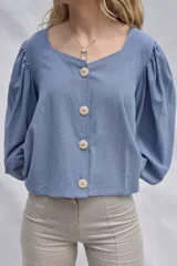 Camisa celeste de muselina 100% algodón, con escote cuadrado, mangas abullonadas 3/4 y cierre frontal con botones de madera.