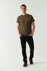 Remera color verde militar con estampado en la espalda con la palabra 'Brookfield' dispuesta verticalmente y diseño geométrico en gris.