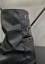 Botas de caña baja negras de cuero sintético, con suela track y tres hebillas decorativas laterales.