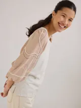 Remera gris de algodón con mangas color beige con bordados de líneas en blanco, amarillo y gris.