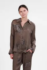 Camisa verde con estampado de leopardos alados, de seda cupro, con cuello clásico, cierre frontal con botones y mangas largas con puños abotonados. Corte holgado.