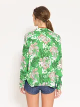Camisa de viscosa con estampado de hongos en tonos verdes, celestes y rosados. Tiene corte relajado, cartera oculta y botones de pasta teñidos a tono con logo marcario.