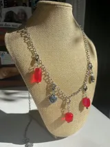 Collar plateado con dijes de corazones y charms colgantes de metal plateado y cuentas rojas.