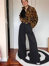 Sweater de peluche con cierre de media cremallera, mitad negro liso y mitad con estampado animal print en tonos marrones y negros.