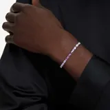 Pulsera plateada con hilera de cristales Swarovski talla baguette en tonos transparentes y morados, con cierre deslizante ajustable.