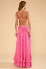 Vestido largo de fiesta color fucsia, con busto estructurado y retorcido en el centro, tirantes finos ajustables, aberturas con volantes en el bajo de la falda, cierre a presión en la parte superior y cremallera invisible en la parte trasera de la cadera.