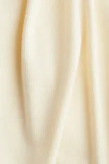 Musculosa corta color crema, de punto acanalado de algodón, con corte ajustado y ribete fino en escote y sisas.